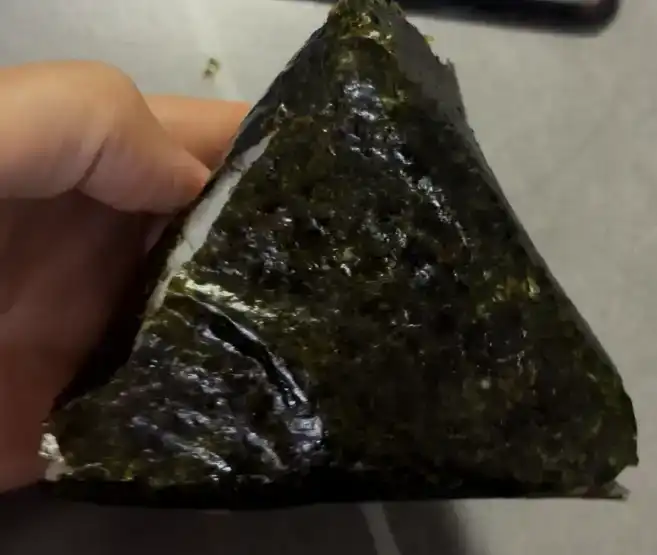 The unwrapped GS25 Perilla Oil Muted Kimchi Tuna Triangle Kimbap showing bare rice