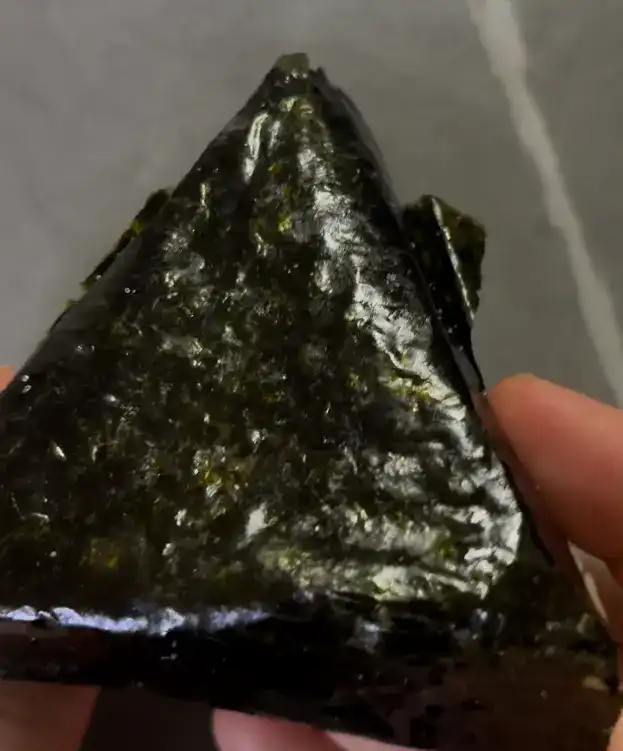 The unwrapped triangle kimbap showing the seasoned soy sauce rice