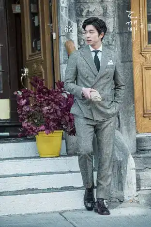 Gong Yoo as the immortal Goblin Kim Shin, walking alone in a stylish long coat through the autumn leaves