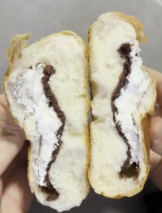 A cross-section of the bread showing the generous cream and red bean filling