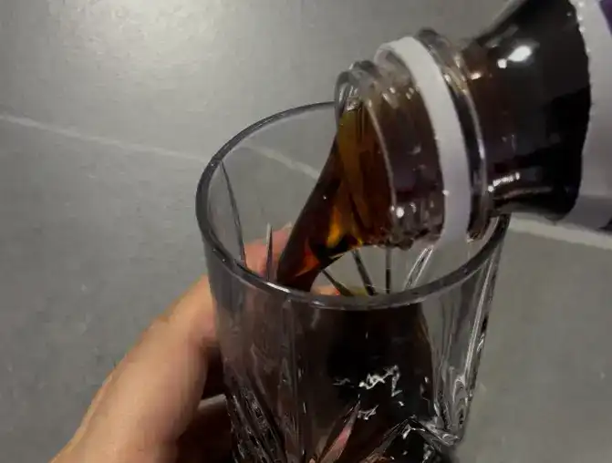 Pouring the dark iced americano into a glass