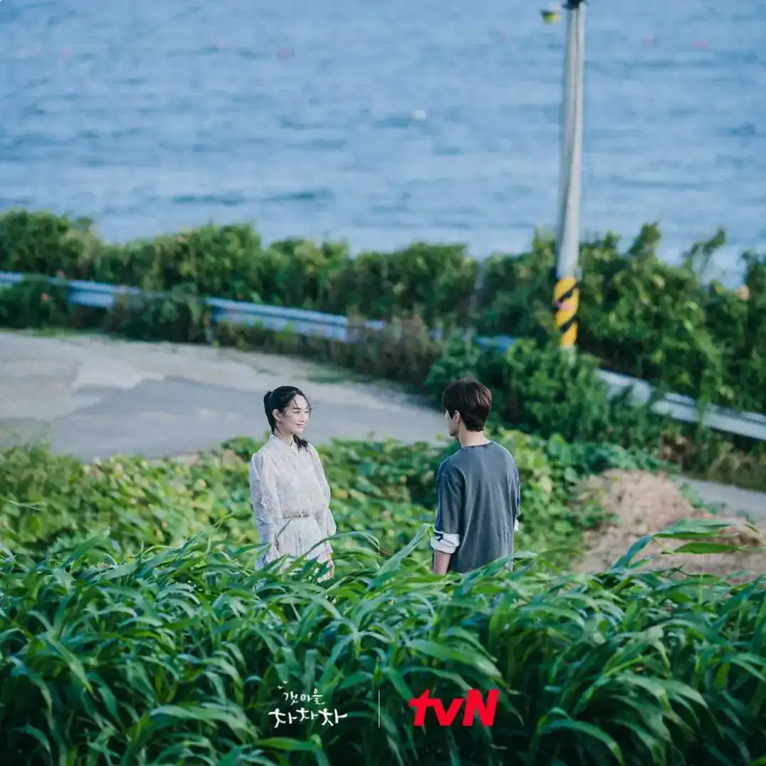 Yoon Hye-jin and Hong Du-sik smiling at each other on a sunny beach, showcasing the romantic chemistry in Hometown Cha-Cha-Cha