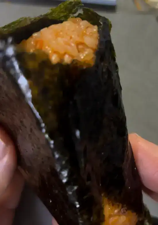 The unwrapped big samgak kimbap showing the red-tinted Jeonju Bibim rice