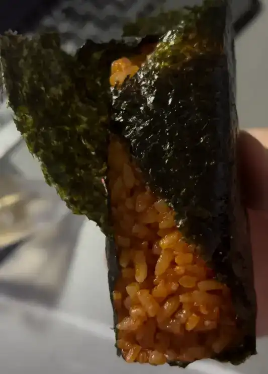 The unwrapped big samgak kimbap showing the vibrant red chili rice