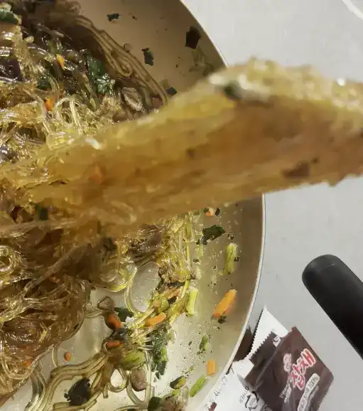 A finished bowl of Ottogi Classic Japchae noodles, glossy with sesame oil and sauce